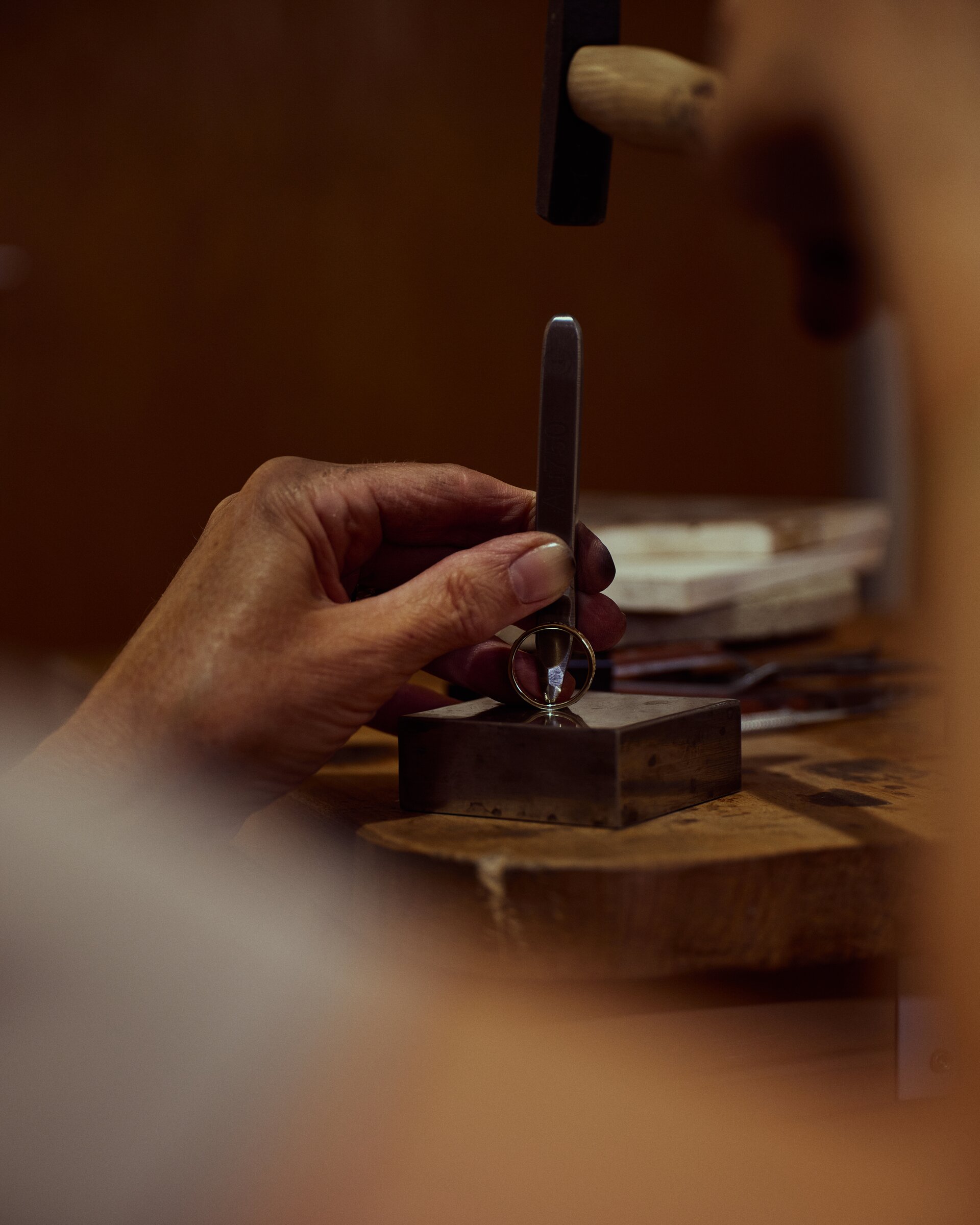 Holding a gold ring with pliers over a steel block