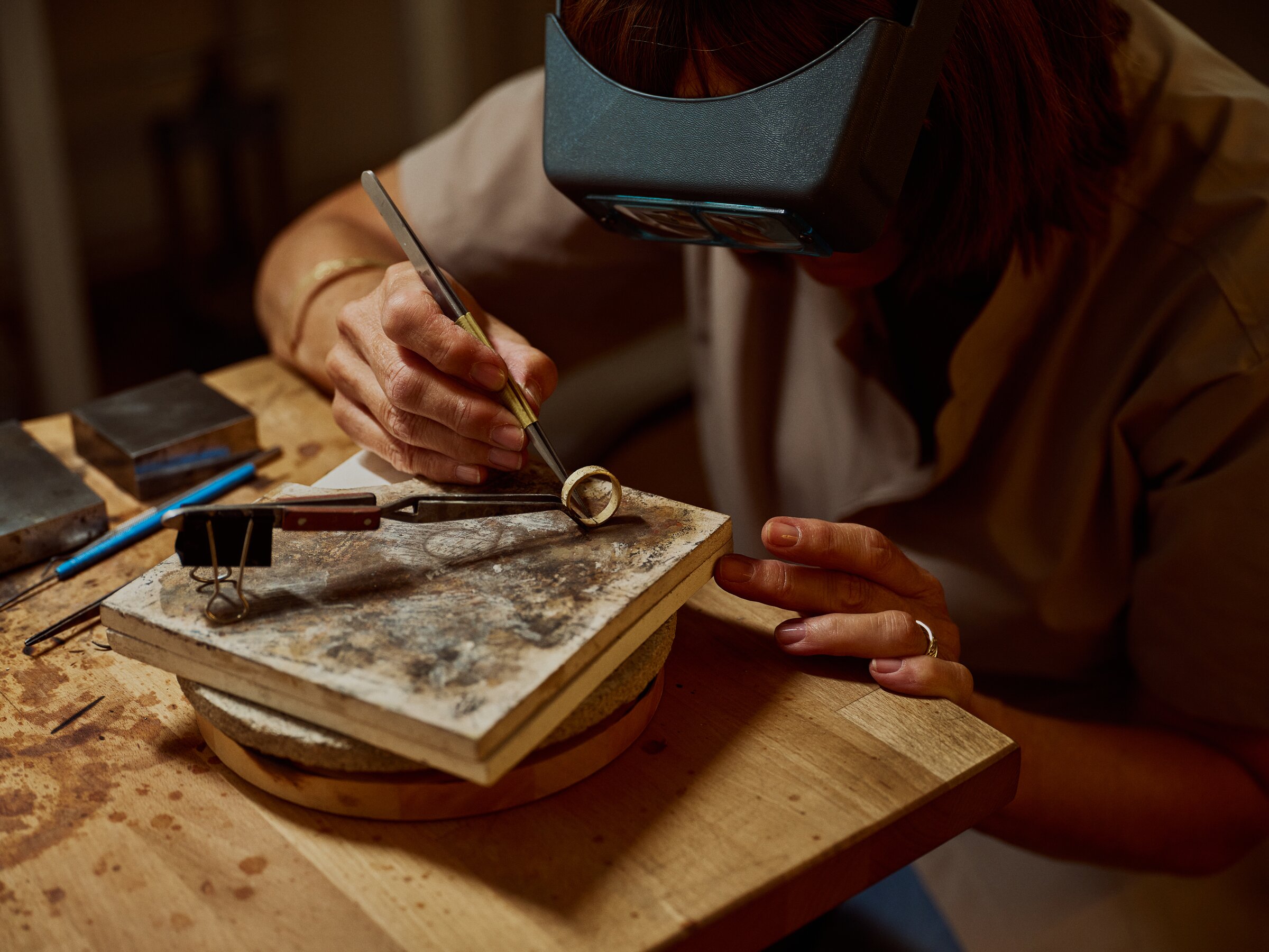 Jeweller examining a gold ring through a loupe visor