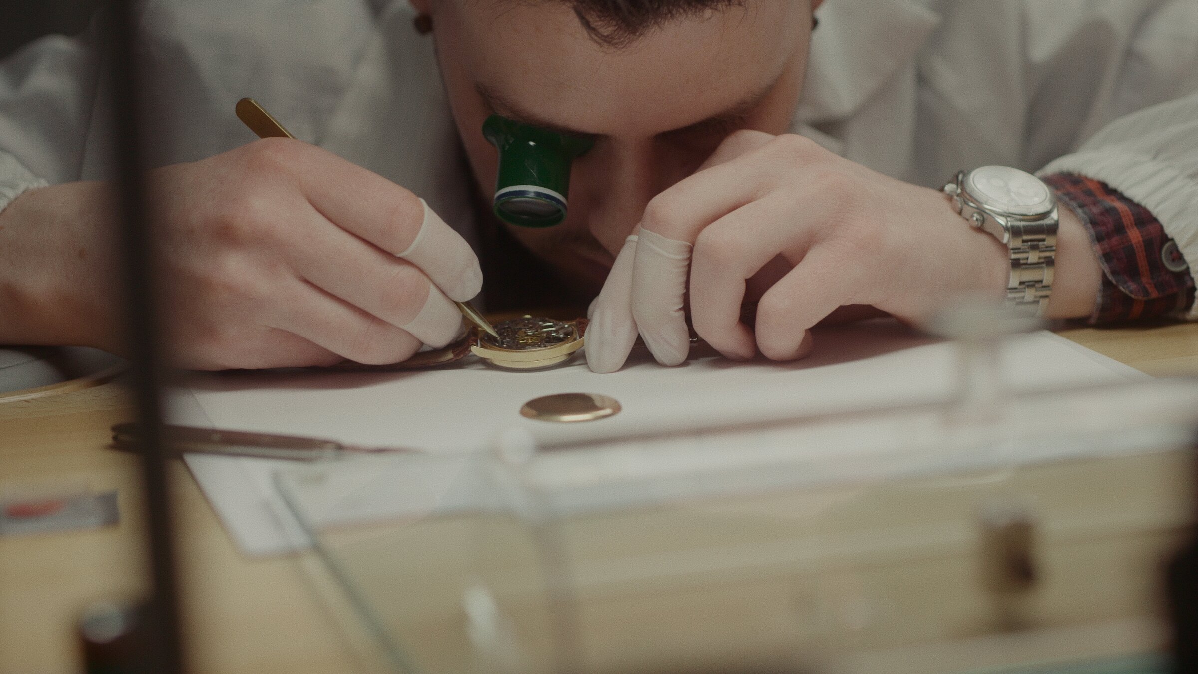 Watchmaker adjusting a watch movement, loupe to the eye