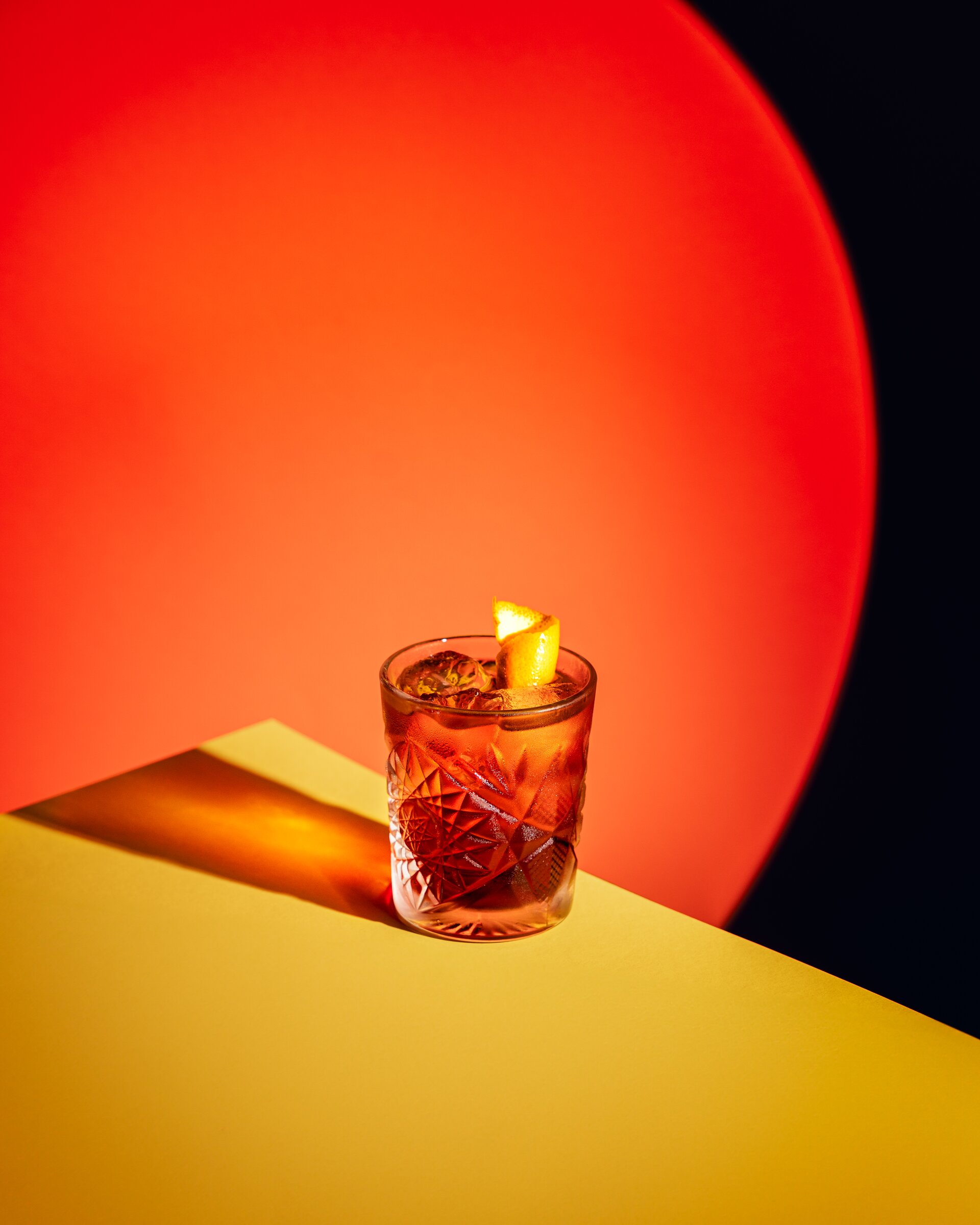 Negroni cocktail with orange twist, bold red and orange backdrop