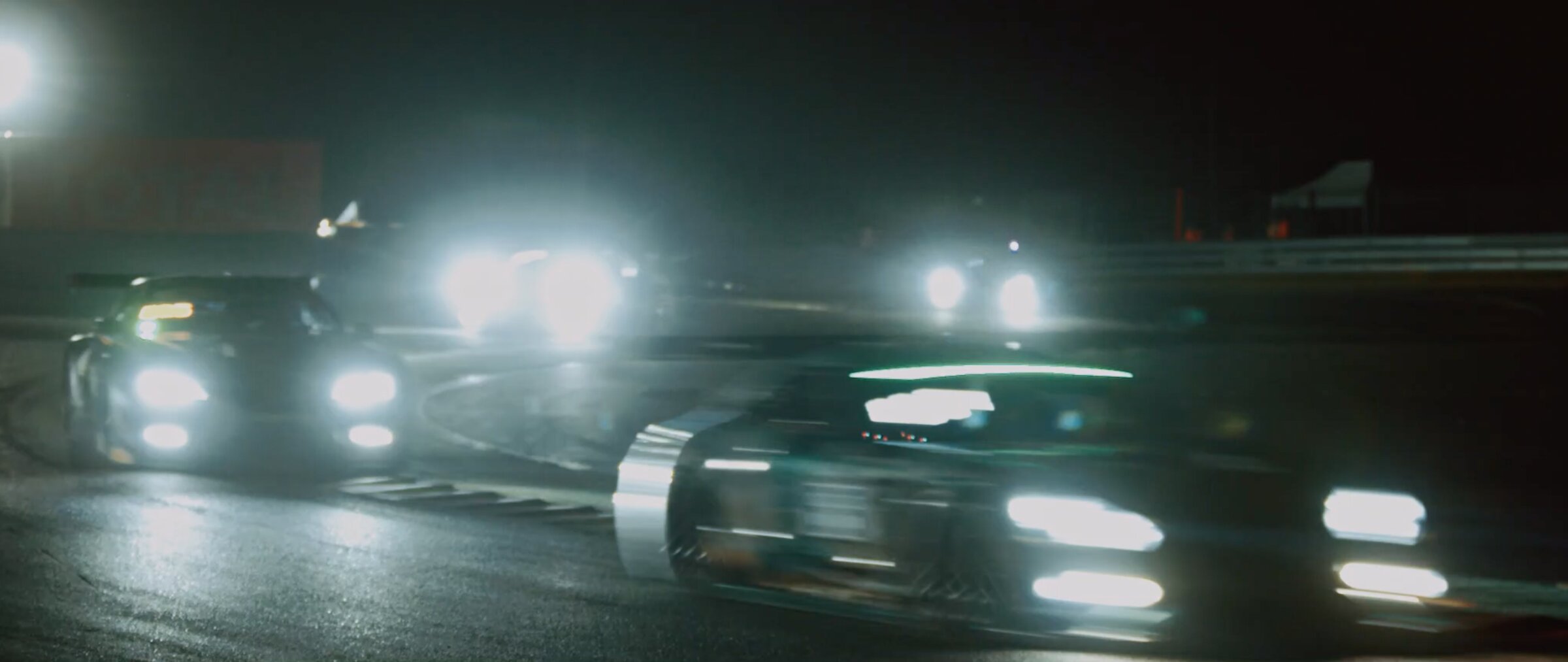 GT cars at night, headlights cutting through mist