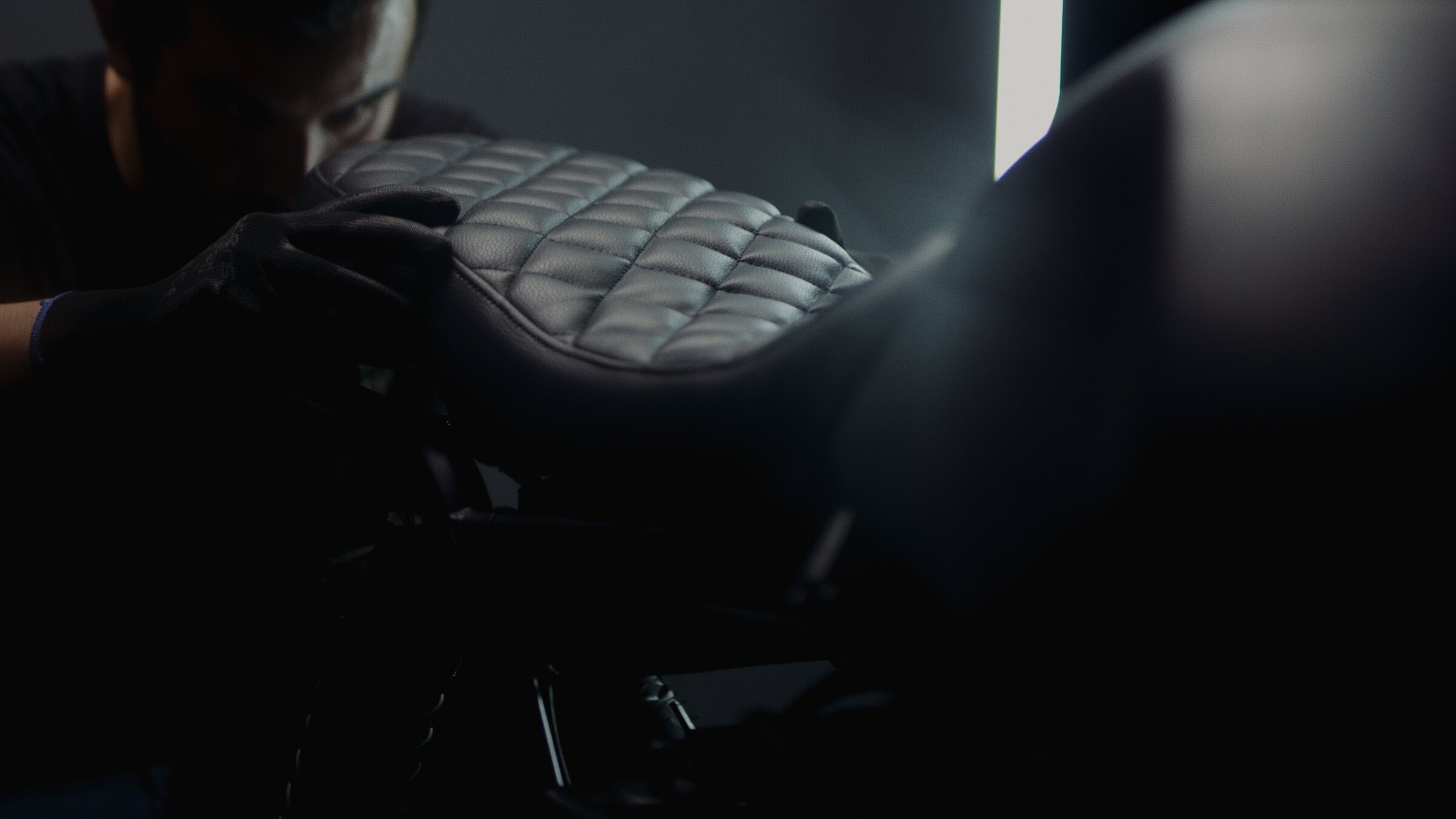 Quilted leather seat detail, mechanic's hands nearby
