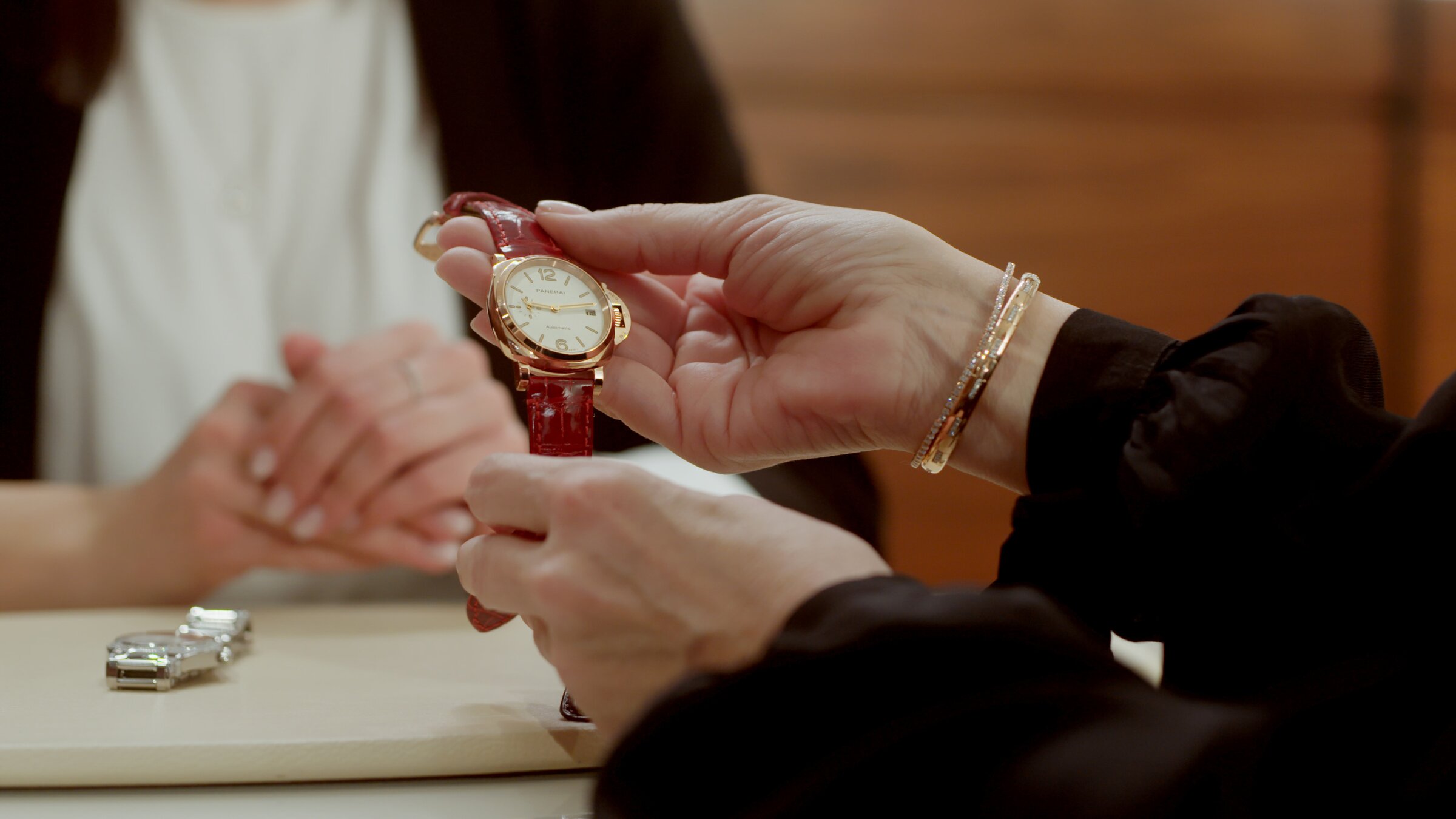 Panerai gold watch with red leather strap, fitting at the counter